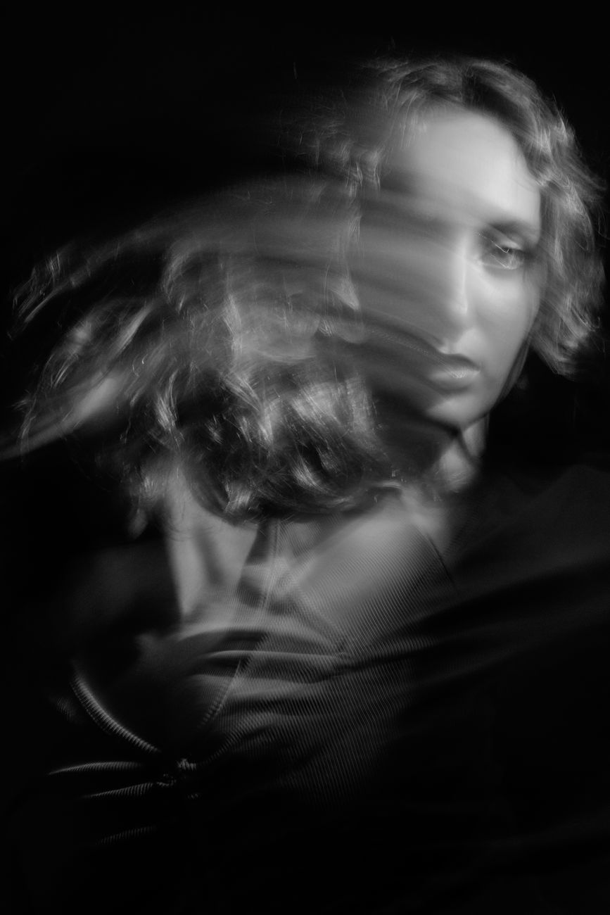 A moody black and white portrait of a woman with artistic motion blur effect.