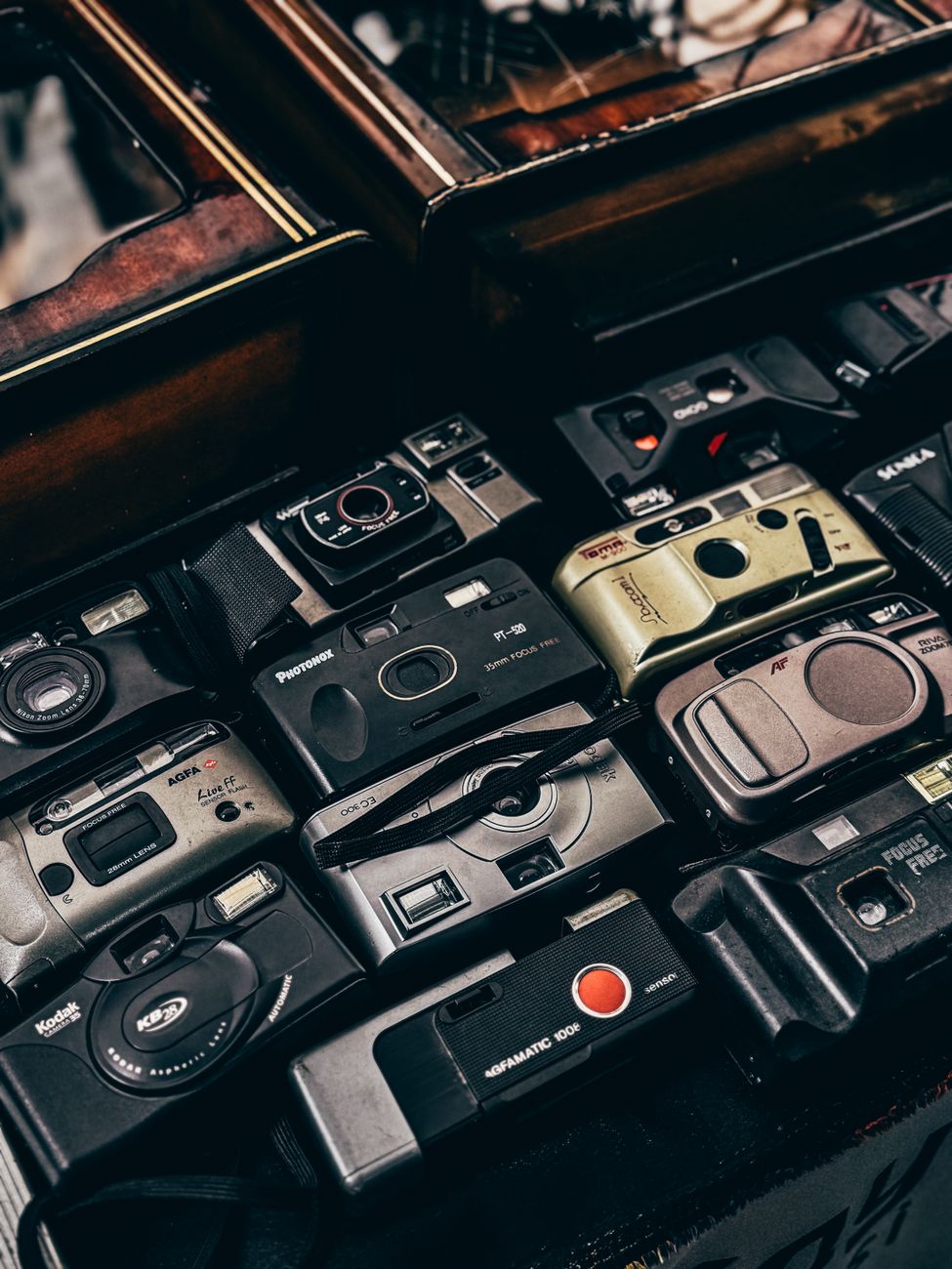 Assorted vintage film cameras arranged in a wooden display box.