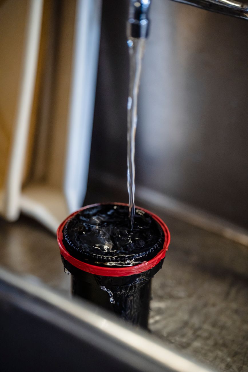 Close-up of water flowing into a film developing tank in a sink.